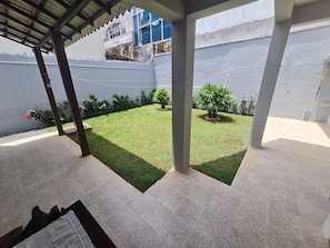 Enjoy a serene outdoor space with a beautifully manicured lawn, potted plants, and a cozy bench.