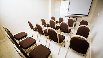 A conference room with rows of chairs, a projection screen, and a whiteboard.