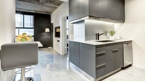 Une cuisine moderne avec des meubles de couleur sombre, une hotte de cuisinière en acier inoxydable et un lave-vaisselle.