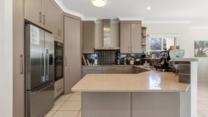 A modern kitchen with stainless steel appliances, a granite countertop, and a large island. - Surfside - Shelly Beach Holiday Home (East Ballina)