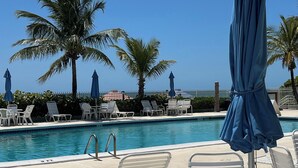 Zona piscina con lettini, ombrelloni e vista libera sulla vasca.