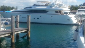 Un grande yacht ormeggiato in una marina, con un molo di legno in primo piano.