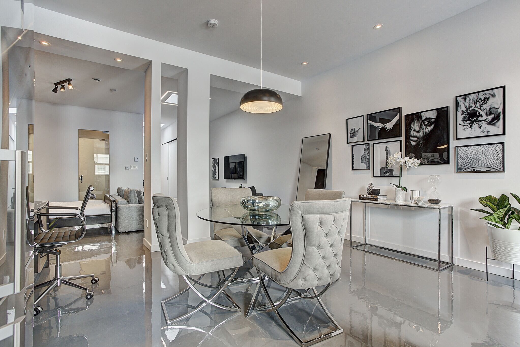 Un comedor moderno con una mesa de vidrio, sillas acolchadas y una decoración minimalista.
