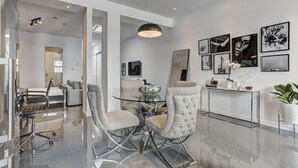 A modern dining area with a glass table, cushioned chairs, and a minimalist decor. - THE YIN | One-Bedroom Loft w. Terrace (Montréal)