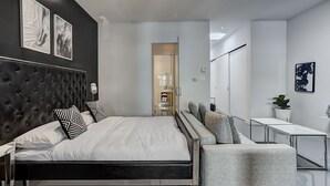 A modern bedroom with a tufted headboard, a large bed, a grey sofa, and a small table. - THE YIN | One-Bedroom Loft w. Terrace (Montréal)