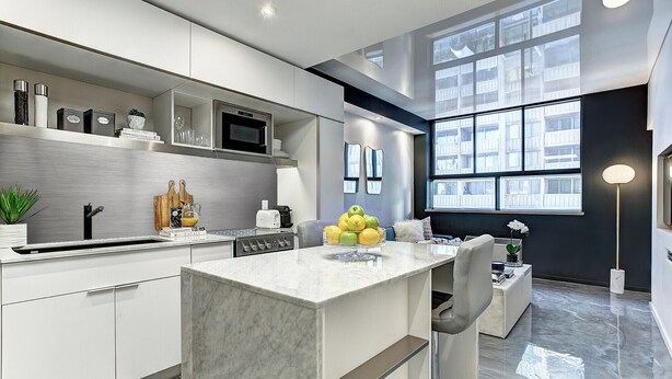 A modern kitchen with a marble island, stainless steel appliances, and a large window providing natural light.