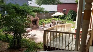 En overdækket terrasse med udendørs møbler, en ildsted i mursten og en træterrasse.