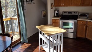 A kitchen with wooden cabinets, a stainless steel oven, a microwave, and a coffee maker. - Cute Beachfront Guest Unit on Lake (Saugatuck)