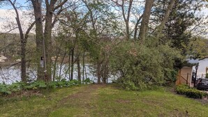 A grassy yard with trees and a small shed. - Cute Beachfront Guest Unit on Lake (Saugatuck)
