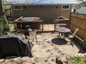 Une terrasse couverte avec un barbecue, une table et des chaises.