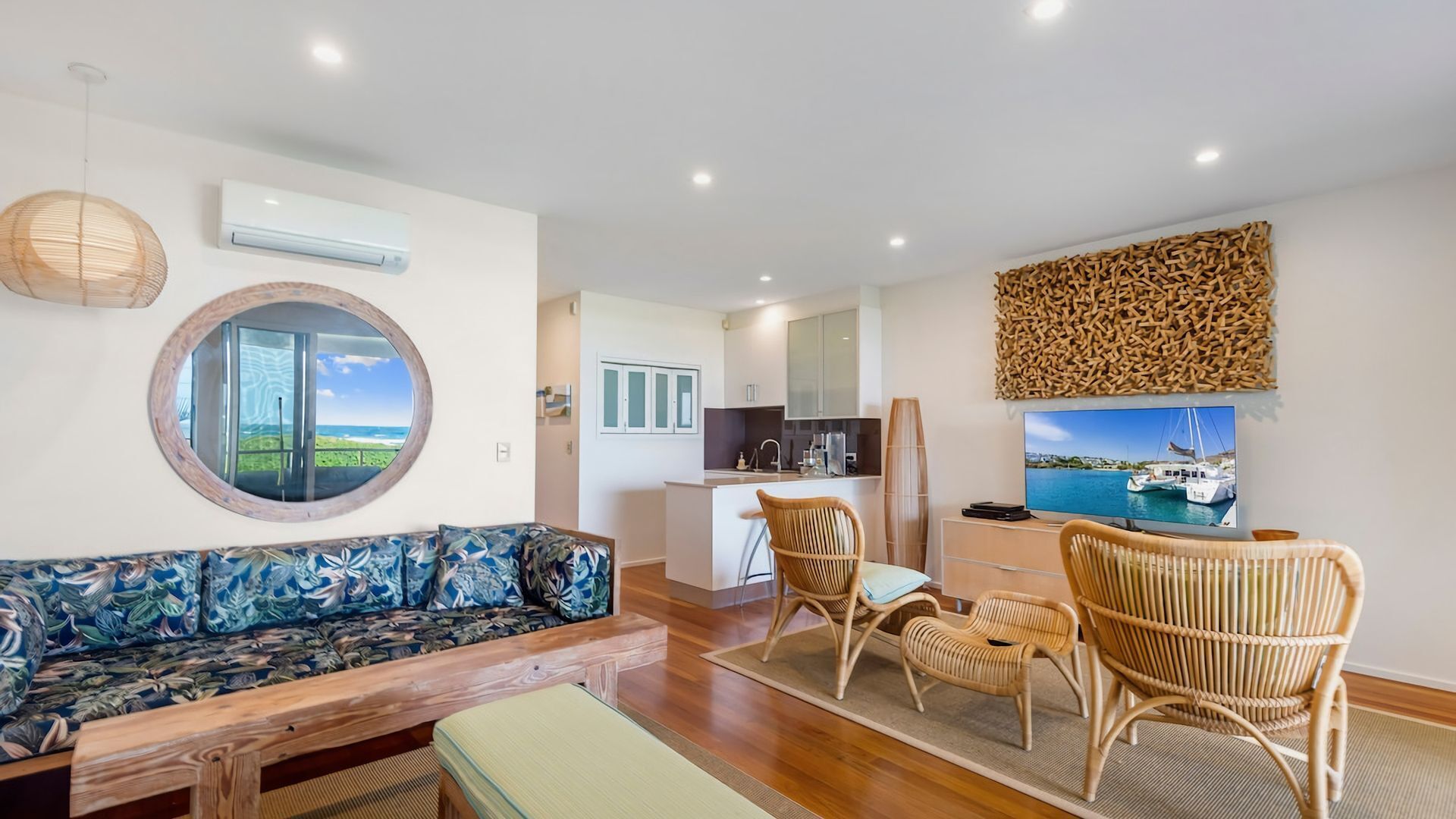 A modern living room with a sofa, chairs, a dining area, and a kitchen.
