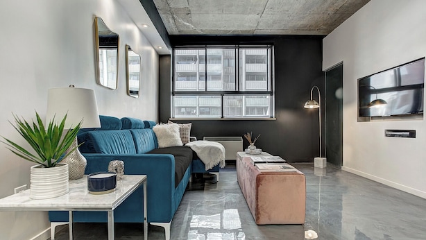 Una sala de estar moderna con un sofá azul, una mesa de centro, un televisor y un ventanal grande.