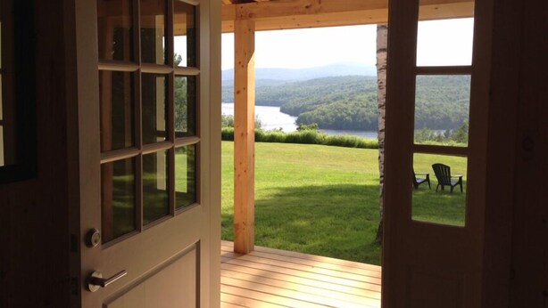 A wooden door leading to a deck with a view of a lake and mountains. - Amazing lake views & access,HotTub & sauna, quality game Rm. 230-10 star Reviews (Wilmington)
