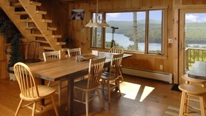A wooden dining area with a table and chairs, large windows with a view of a lake, and a staircase. - Amazing lake views & access,HotTub & sauna, quality game Rm. 230-10 star Reviews (Wilmington)