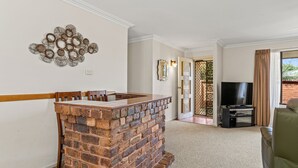 Una sala de estar con chimenea de ladrillo, televisor y sofá.