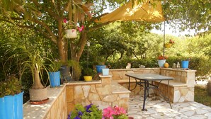 An outdoor patio with stone walls, a table, and various potted plants. - In Villa Nikoli private apartment sleeps 5 AMA 223322 (Lefkimmi)