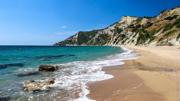 A beach with clear blue water, sandy shore, and rocky cliffs. - In Villa Nikoli private apartment sleeps 5 AMA 223322 (Lefkimmi)