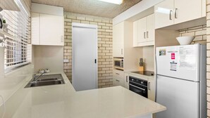 A compact kitchen with a sink, a microwave, a refrigerator, and a dishwasher.