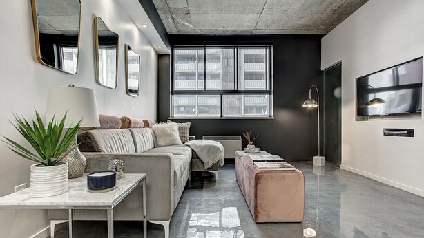 Ein modernes Wohnzimmer mit einer Couch, einem Couchtisch und einem an der Wand befestigten Fernseher.