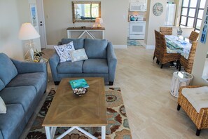 Un salon comprenant un canapé, une table basse et un coin repas avec des chaises en osier.
