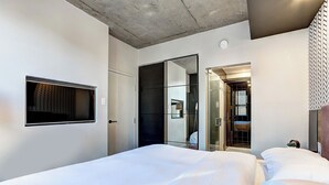 Une chambre d’hôtel moderne avec un grand lit, une armoire et un miroir.