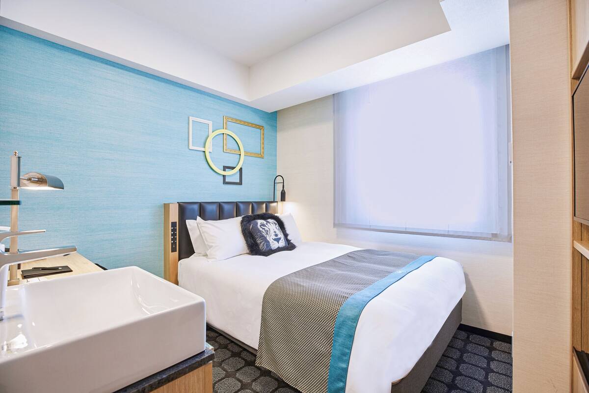 Une chambre d’hôtel avec un grand lit, une table de chevet, un lavabo et une fenêtre donnant sur un beau paysage.