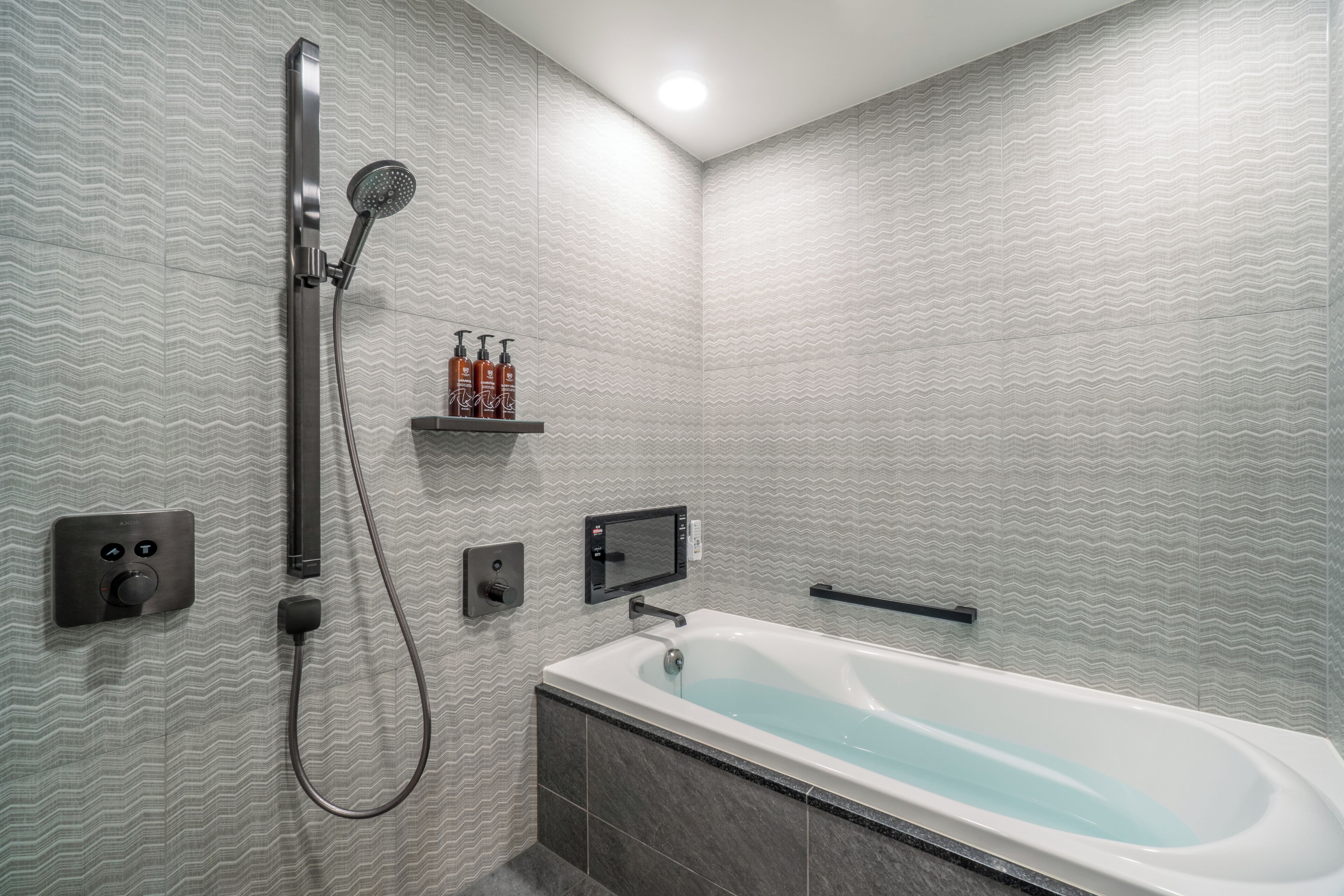 Un baño moderno con una bañera independiente, un cabezal de ducha manual y un panel de control en la pared.