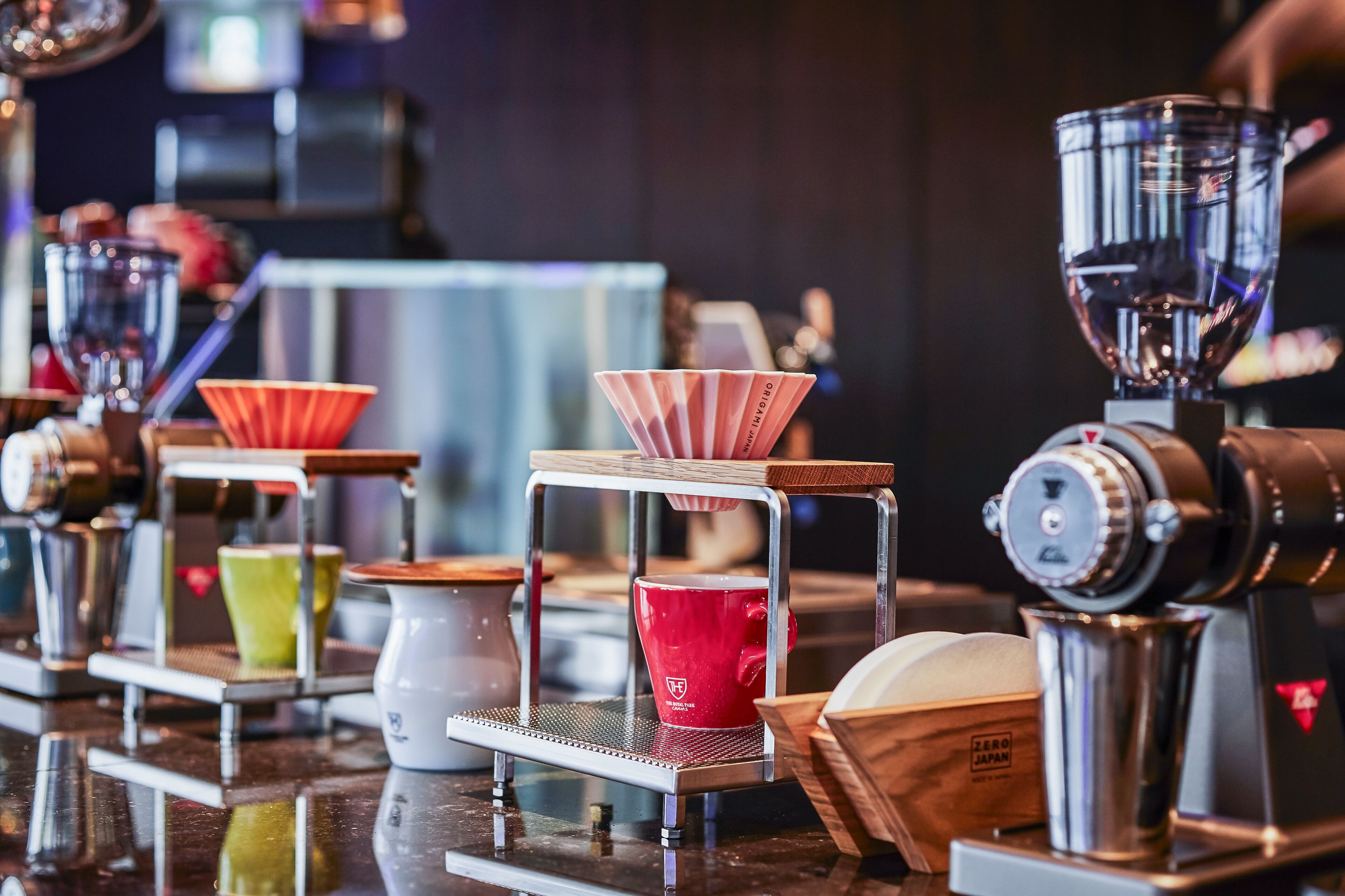 A coffee machine with a grinder and a drip coffee maker, with a red cup and a green cup on the counter.