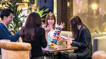 Un grupo de personas sentadas alrededor de una mesa con una pila de bloques de colores, una botella de agua y una de refresco.