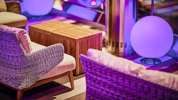 Ein stilvoller Lounge-Bereich mit Korbmöbeln, einem Holztisch und stimmungsvoller Beleuchtung.