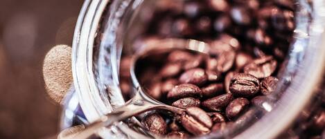 A close-up of a glass jar filled with coffee beans and a spoon.