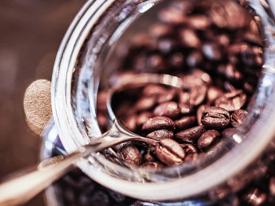 Ein Nahaufnahme eines Glases, gefüllt mit Kaffeebohnen und einem Löffel.