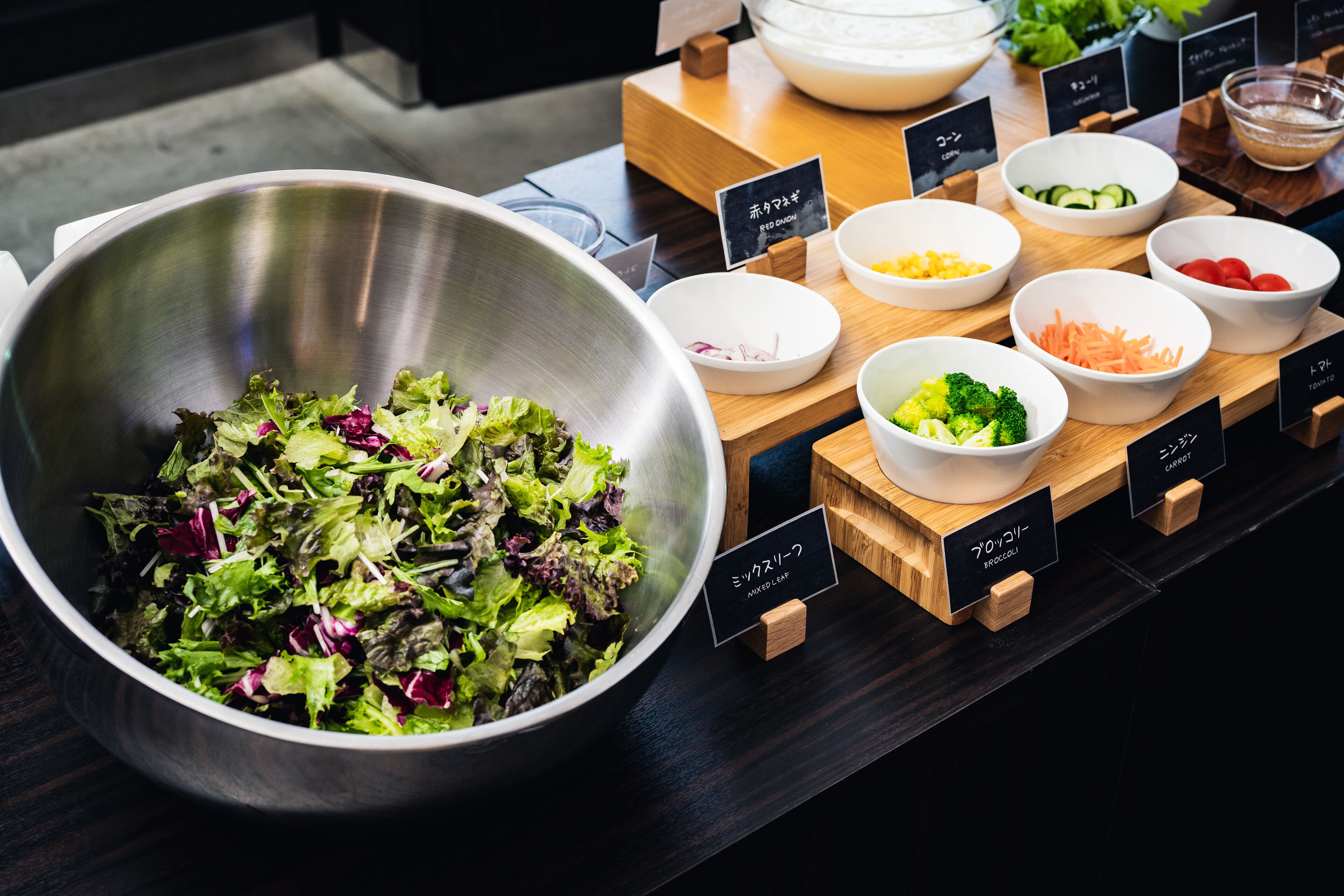 Un buffet à salades proposant une variété de légumes et un grand saladier rempli de différentes sortes de salades.