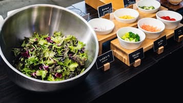 Un buffet à salades proposant une variété de légumes et un grand saladier rempli de différentes sortes de salades.