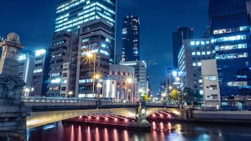 Une vue nocturne d’une ville, avec des bâtiments illuminés, un pont et une rivière.