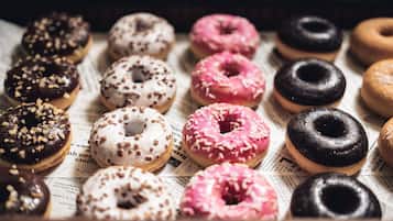 A variety of donuts arranged on a newspaper.