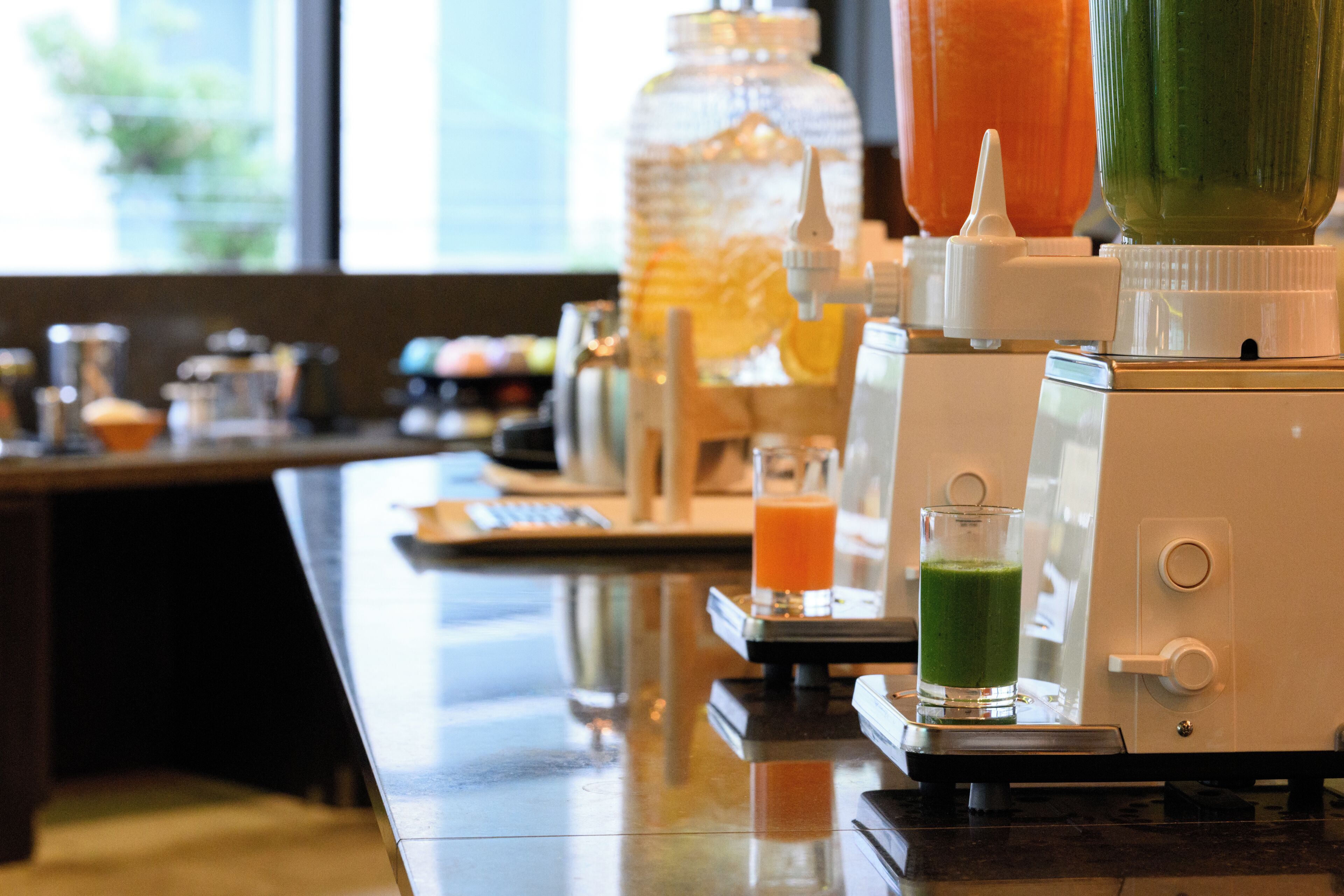 A bar area with a juicer, a blender, and a glass of green juice.