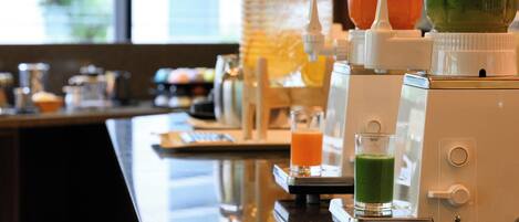 A bar area with a juicer, a blender, and a glass of green juice.