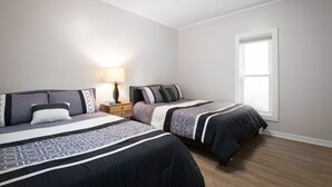 Een slaapkamer met twee bedden, een nachtkastje, een lamp en een raam.