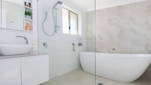 A modern bathroom with a freestanding bathtub, a large mirror, and a shower. - Kay's Hideaway (Lennox Head)