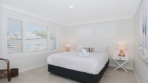 A bedroom with a bed, two bedside tables, and a chair. - Kay's Hideaway (Lennox Head)