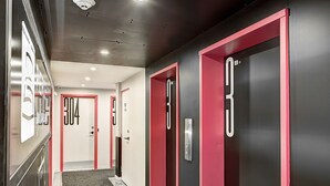 Un pasillo de hotel con puertas enmarcadas en rojo, con los números 304 y 303.