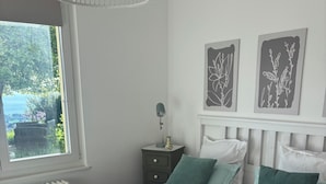 Un dormitorio con una cama, una mesita de noche, una lámpara y dos cuadros en la pared.