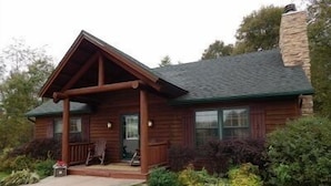 A wooden cabin with a porch, stone chimney, and a well-maintained lawn. - Apple Canyon Lake, Game Room, Hot Tub (Apple River)