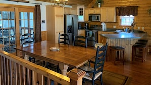 A wooden cabin interior with a dining area, kitchen, and a large window. - Apple Canyon Lake, Game Room, Hot Tub (Apple River)
