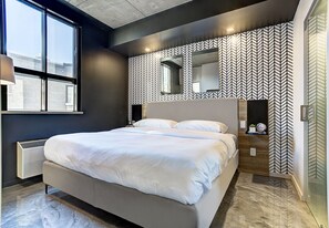 Une chambre moderne avec un grand lit, une fenêtre et un mur décoré d’un motif.