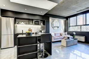 Une cuisine moderne dotée d’un îlot central intégré, de tabourets de bar et d’un coin salon avec un canapé et une table basse.