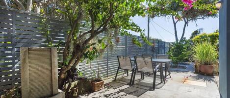 A patio area with a table and chairs, a potted plant, and a fence.