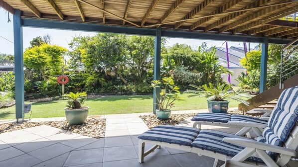 Un espace extérieur aménagé, abrité et doté de fauteuils confortables et de plantes en pot.