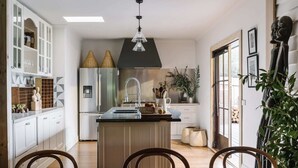 A modern kitchen with a central island, stainless steel appliances, and a black hood above the stove. - The Oxford ~ Hepburn Springs/Daylesford ~ Sleeps 24 (Hepburn Springs)